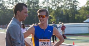 Dave Klink op de atletiekbaan in gesprek met een deelnemer van de Gouden Spike.