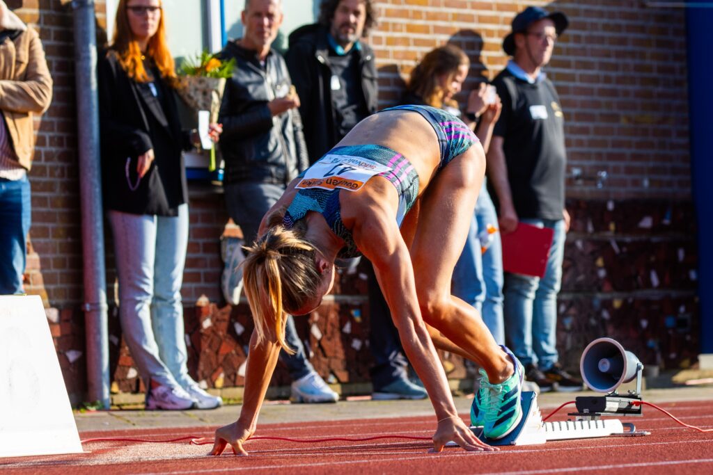 Een atlete in de startblokken is klaar om weg te sprinten.